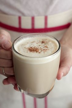 a person holding a drink in their hand with cinnamon sprinkles on top