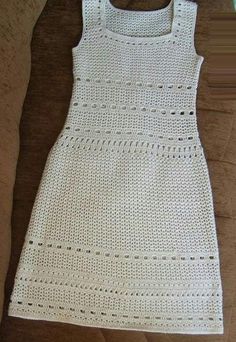 a white crocheted dress laying on top of a wooden floor