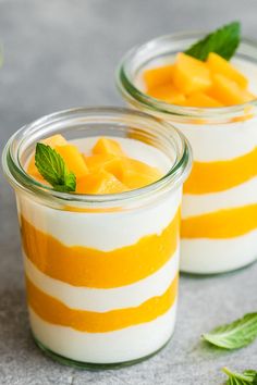 two small jars filled with fruit and yogurt on top of a gray surface