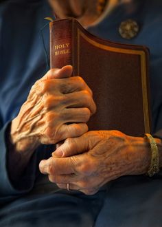 an old woman holding a bible in her hands