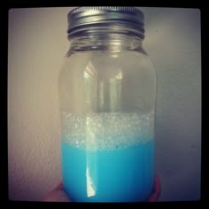 a hand holding a jar filled with blue liquid