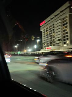 cars are driving down the street at night in front of tall buildings and skyscrapers