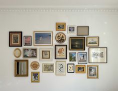 a wall with many different framed pictures on it