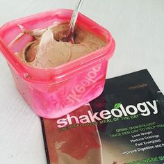 a pink container filled with chocolate ice cream next to a book on top of a table