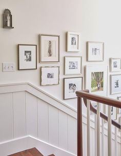 there are many framed pictures on the wall next to the bannister and stairs