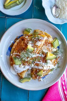 an omelet with cucumbers and other toppings on a white plate