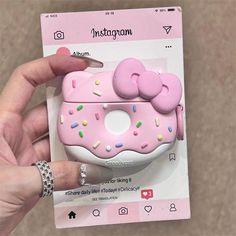 a person holding up a pink hello kitty doughnut airpods case