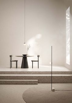 an empty room with two chairs and a table on the floor, in front of a white wall