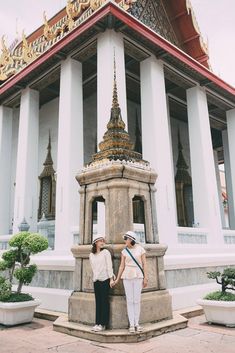 two women standing next to each other in front of a building with columns and arches