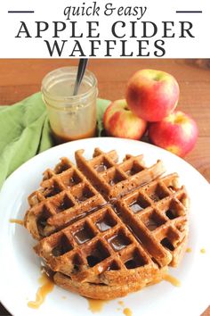 a white plate topped with waffles covered in syrup next to apples and a jar of apple cider