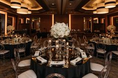 an elegantly decorated banquet room with black tablecloths and white flower centerpieces