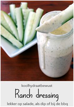 a jar filled with ranch dressing next to sliced cucumbers on a white plate