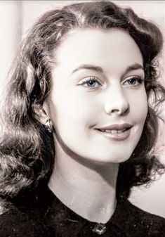 a black and white photo of a woman with curly hair smiling at the camera,