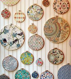 there are many plates on the wall with different designs and colors in them, all hanging up