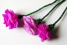 three pink flowers with green beads on a white surface, one is hanging from a string