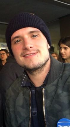 a man wearing a black hat and jacket in front of a group of young people