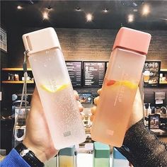 two people holding up their drinks in front of the counter at a coffee shop or restaurant