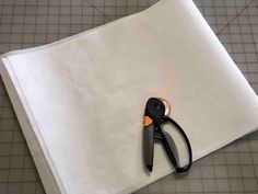 a pair of scissors sitting on top of a piece of white paper next to a hole punch