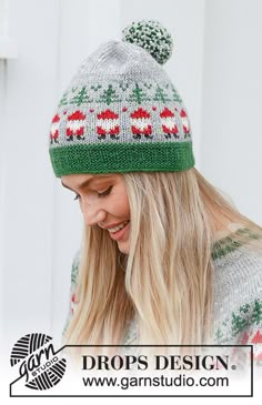 a woman wearing a green and red knitted hat with pom - poms