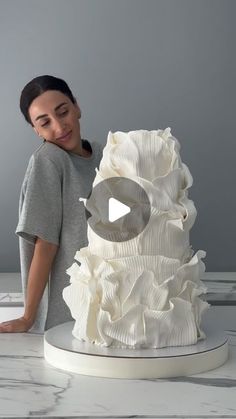 a woman standing next to a white cake