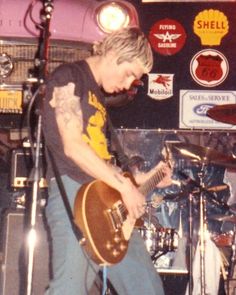 a young man playing guitar in front of a microphone and some stickers on the wall