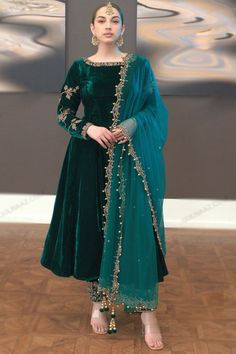 Bright and colorful, this teal green velvet trouser suit features beautiful embroidery work.This round neck and full sleeve suit is designed with stone and dabka work.Along with velvet trouser pants in teal green color with teal blue net dupatta.Trouser pants has stone and dabka work.Dupatta designed using beads, stone, pearl, and dabka work.This trouser suit can be customised up to maximum size available in inches 68. Slight color variation may occur due to photographic reasons. Velvet Suite Design, Velvet Dress Colors, Walwet Suit Designs, Velvate Dress Design Gown, Velvet Salwar Suit Designs, Bottle Green Dress Outfits, Valvet Suite Design, Winter Wedding Outfits Indian, Green Nikkah Dress