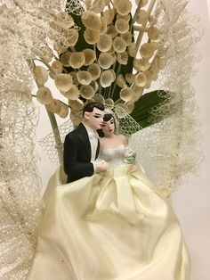 a bride and groom figurine sitting next to each other