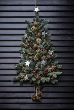 a small christmas tree with pine cones and stars hanging from it's sides, against a black background