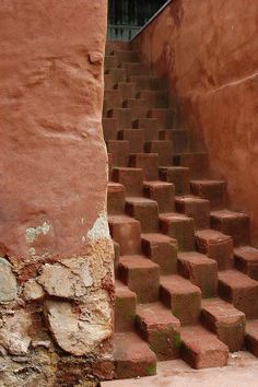 a cat sitting on the steps leading up to a building that has red brick walls