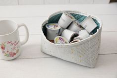 a cup filled with lots of different types of items next to a mug on a table