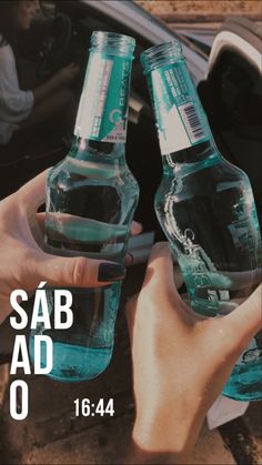 two people holding up bottled water in front of a car with the words sab ad on it