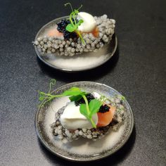 two small plates with food on them sitting on a black counter top next to each other