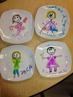 four plates with children's drawings on them sitting on top of a wooden table