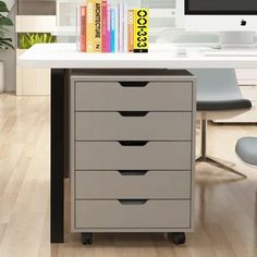 an office desk with a computer monitor and books on it