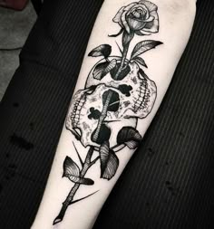 a skull and rose tattoo on the arm