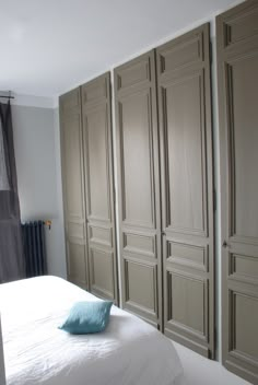 a white bed sitting in a bedroom next to wooden closets