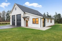 a large white barn with two garages on the front and one door open to let in light