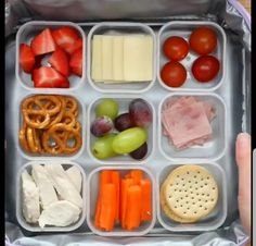 a lunch box filled with different types of food and cheese, crackers, fruit, and vegetables