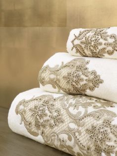 three towels stacked on top of each other in front of a gold wall with an intricate design