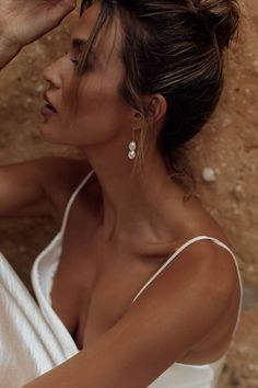 a woman in a white dress is holding her hair