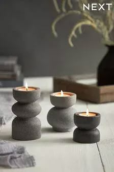 three lit candles sitting on top of rocks