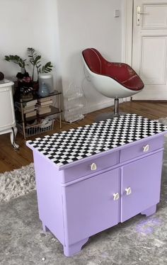 a purple dresser sitting on top of a rug next to a chair