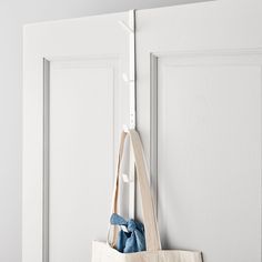 a tote bag hanging on the side of a white door with a blue bow