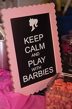 a sign that says keep calm and play with barbies next to some baked goods