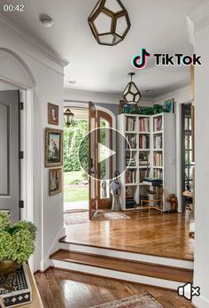 the inside of a house with wood floors and bookshelves in front of it