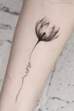 a black and white photo of a flower with the word love tattooed on it's arm