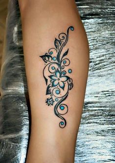 a tattoo on the leg of a woman with blue flowers and swirls around it