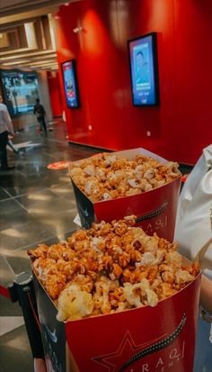 three red buckets filled with popcorn sitting on top of a table