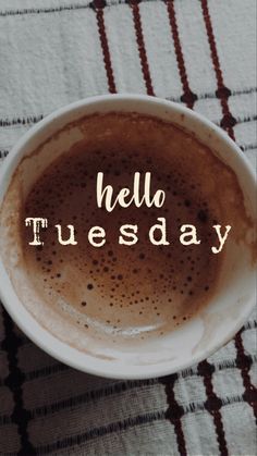 a white bowl filled with liquid sitting on top of a checkered table cloth next to a cup of coffee