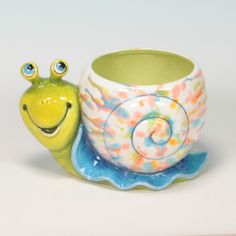 a ceramic snail sitting on top of a cup